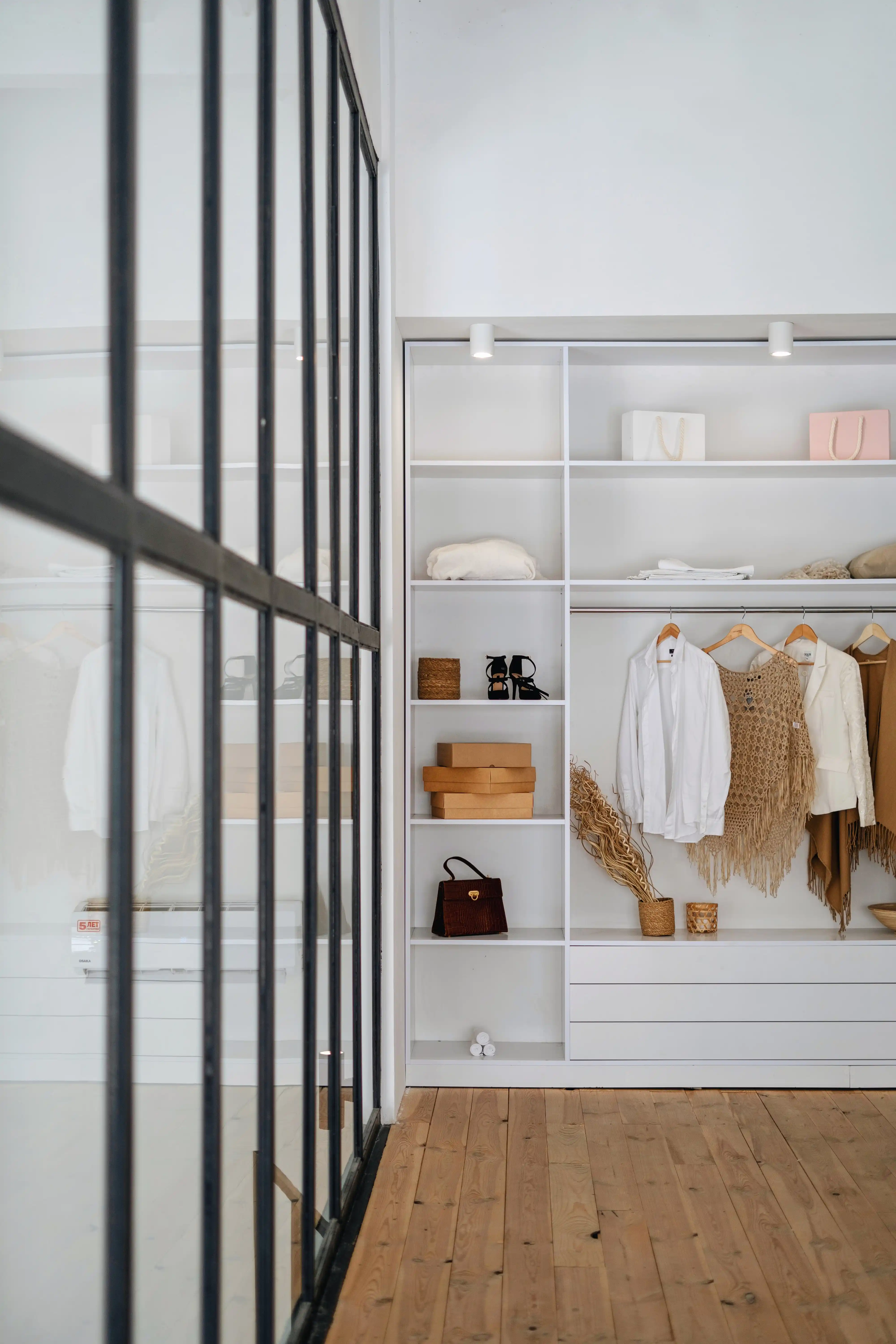 A closet with clothes hanging up and shoes on shelves